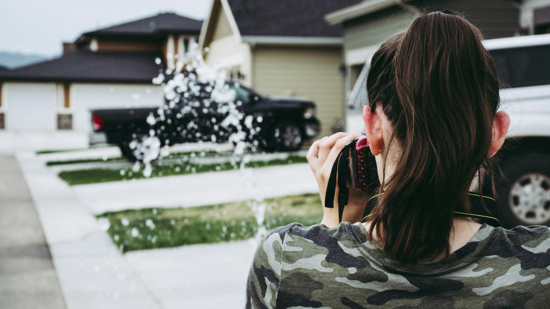 Young woman photographer focusing on urban street with camera in hand.