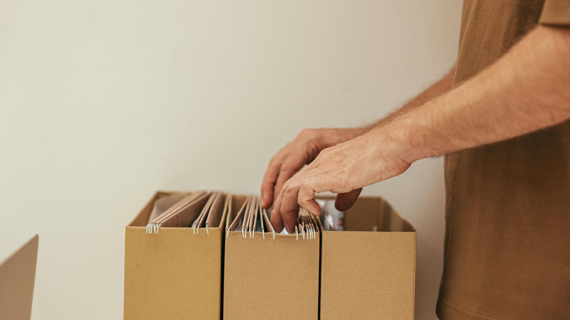 Close-up of a person organizing files in cardboard boxes, ideal for business and office themes.