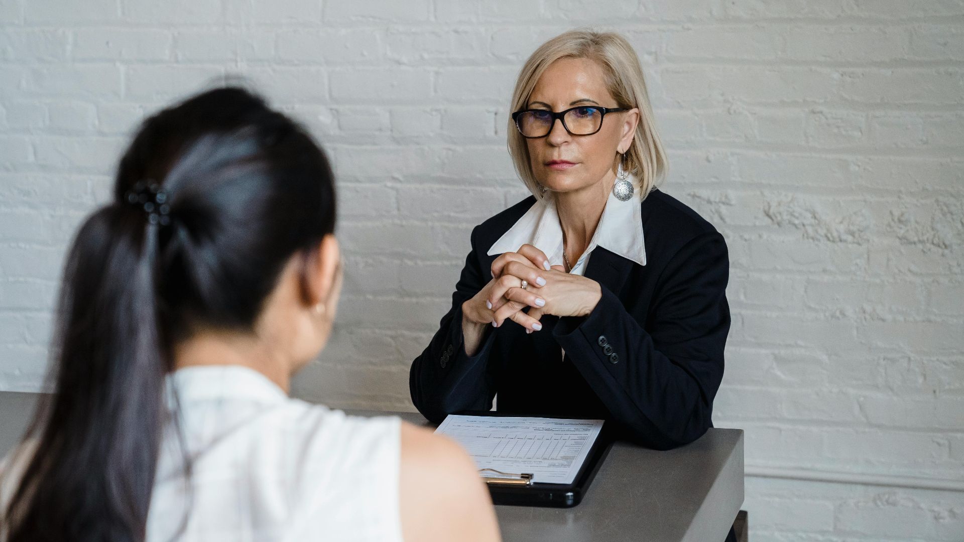 Professional businesswoman in a black blazer conducting an interview indoors.