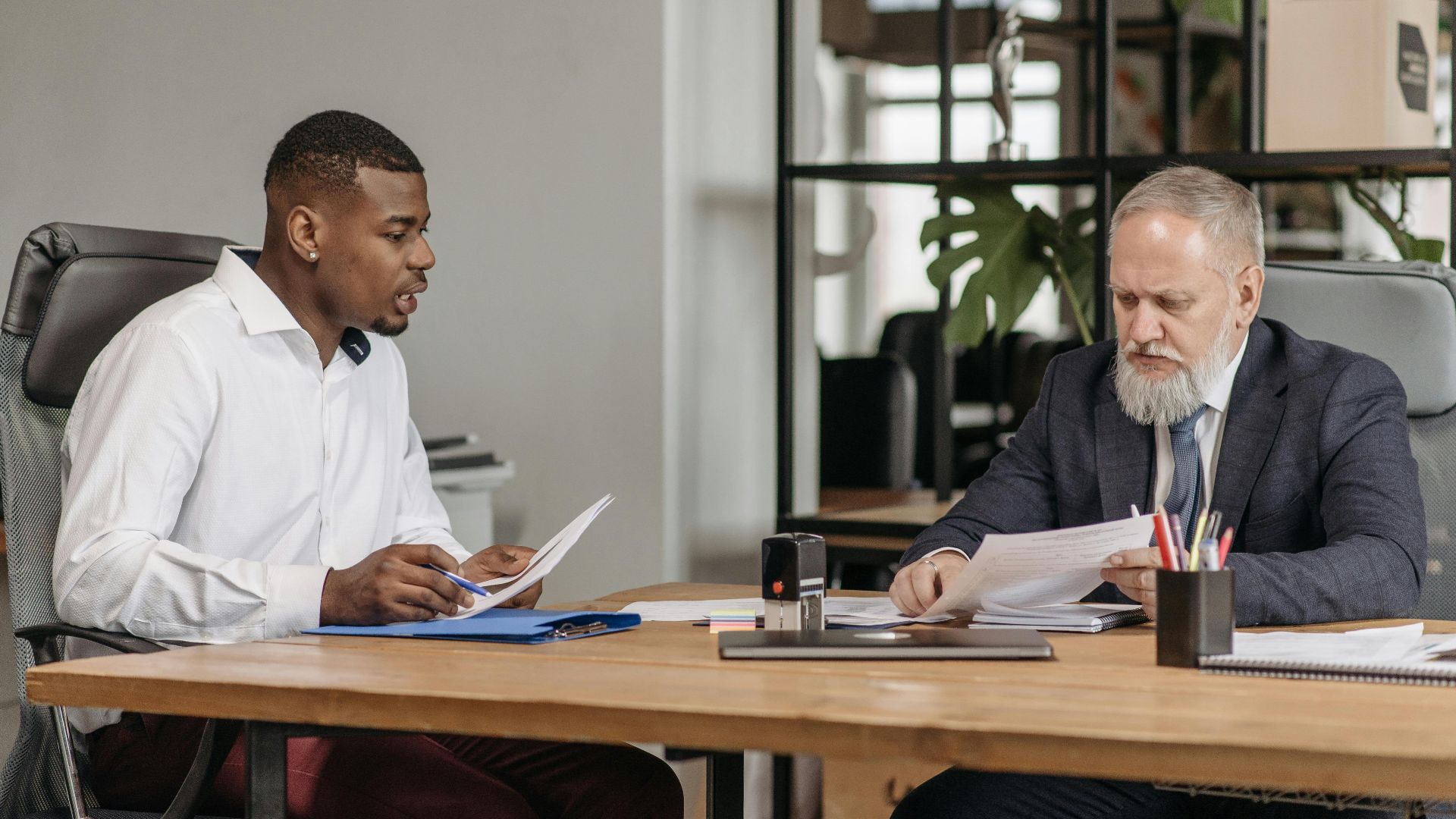 Two businessmen discussing documents during a meeting in a modern office.