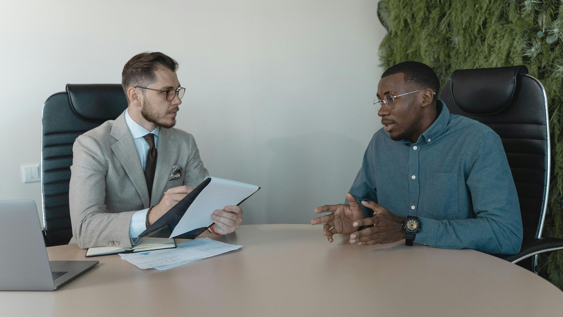 Two businessmen engaged in a discussion during a job interview in a contemporary office environment.
