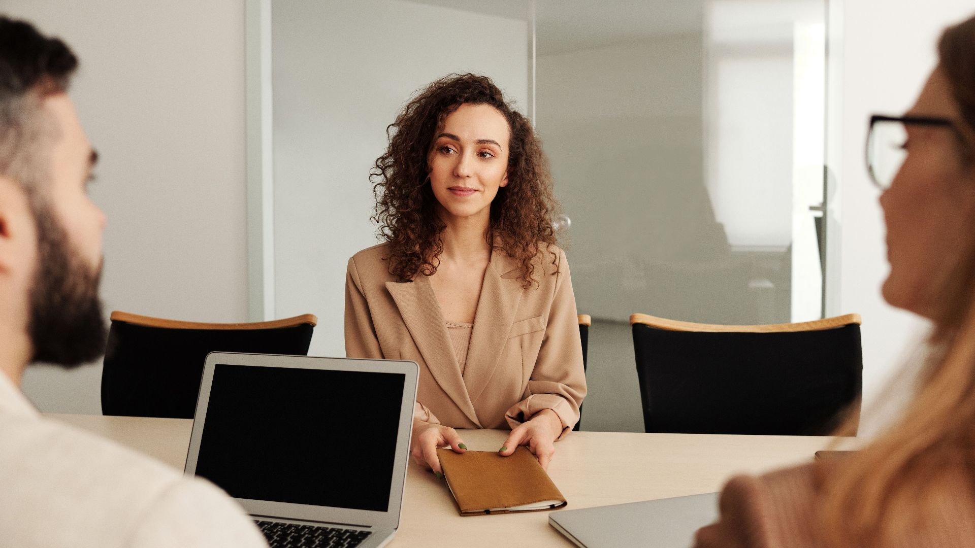 A woman in a business suit participates in a job interview, showcasing professionalism and modern office environment.