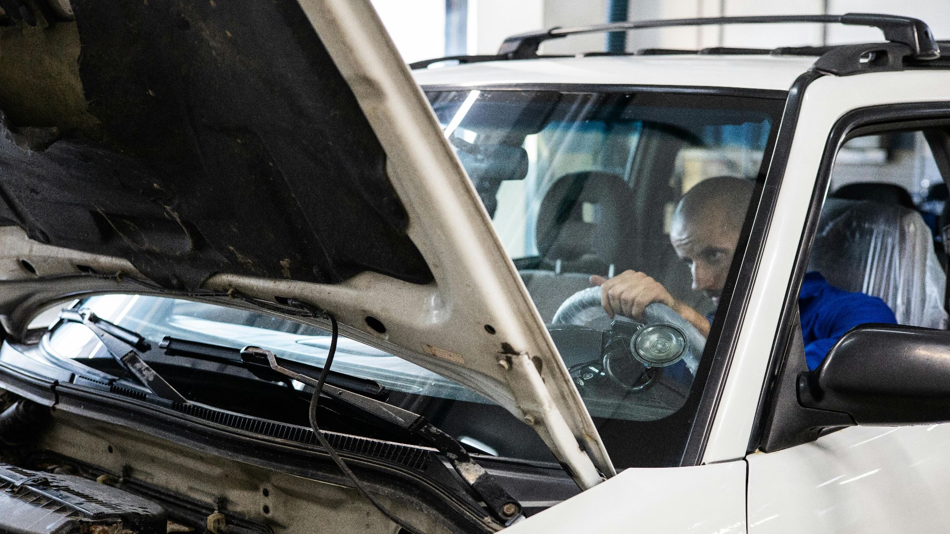 A mechanic performs a detailed inspection on a vehicle in a workshop setting.