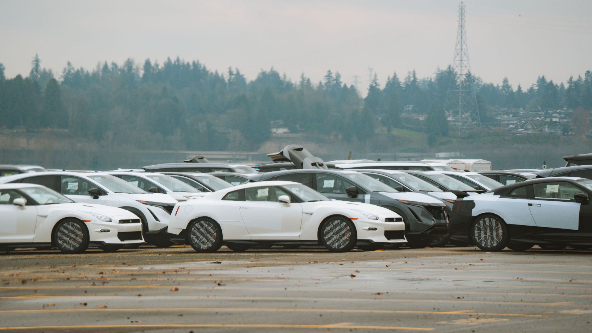 Wide shot of multiple sports cars parked outdoors on a cloudy day.