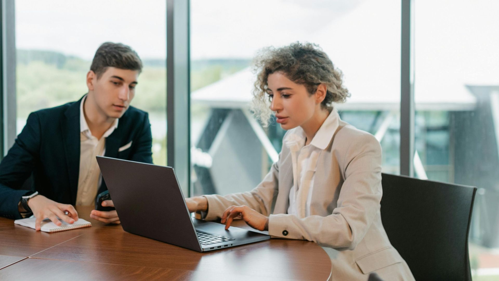 Two colleagues engaged in a business meeting in a well-lit modern office space.