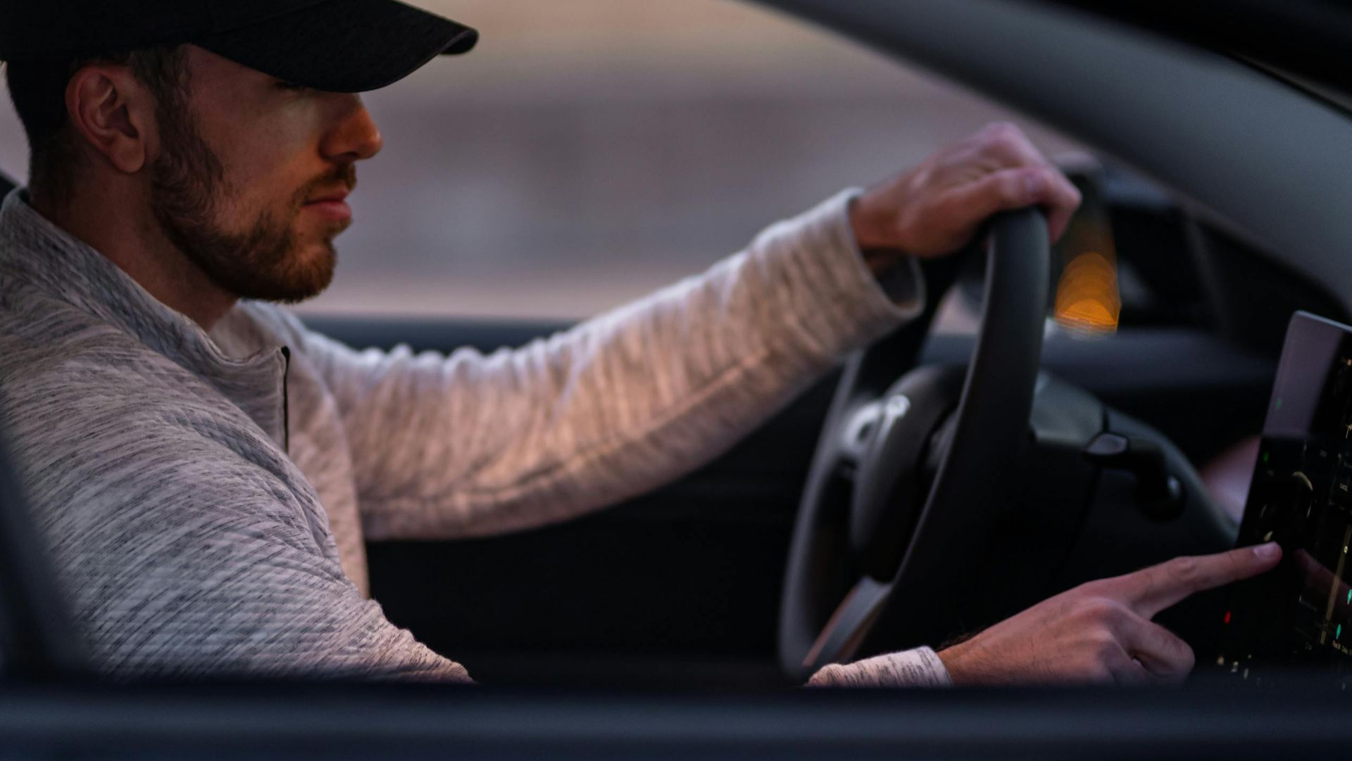 A man interacts with a touchscreen inside an electric car, driving through Dallas, TX.