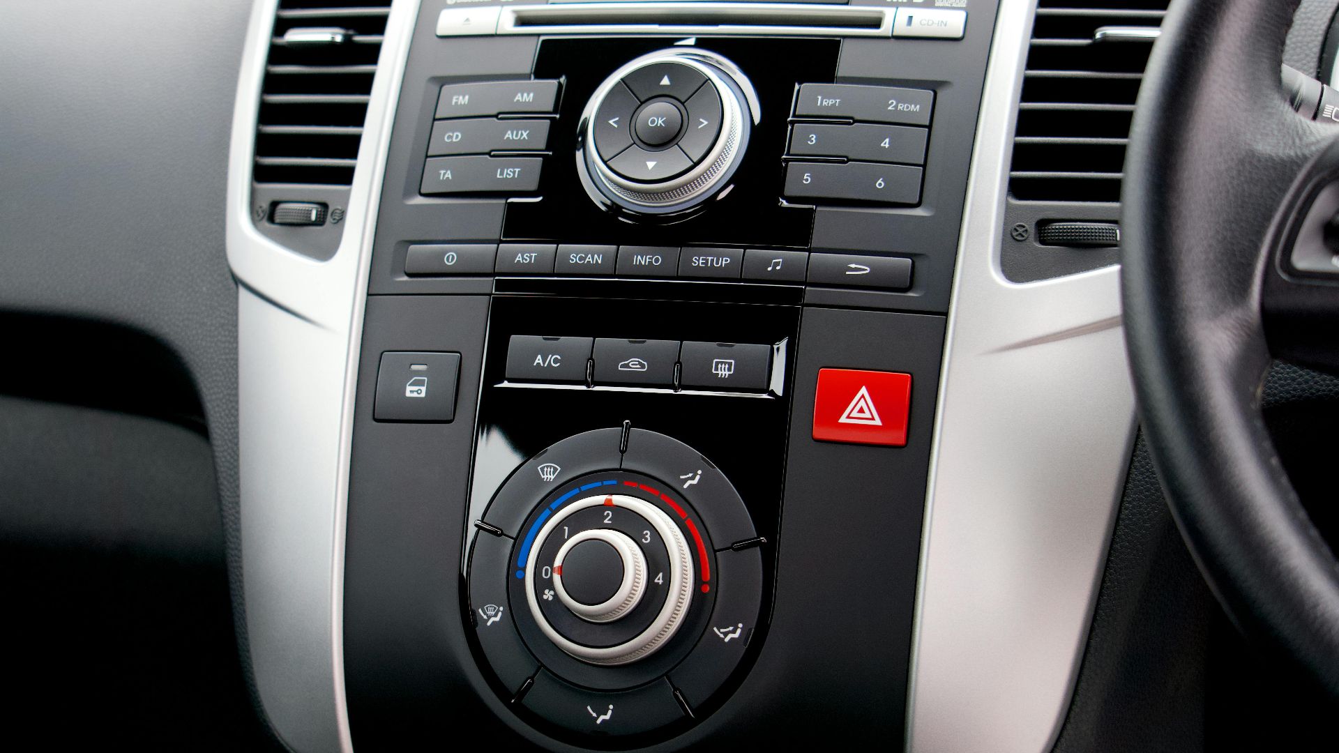 Close-up of a car's dashboard featuring buttons, dials, and a steering wheel.