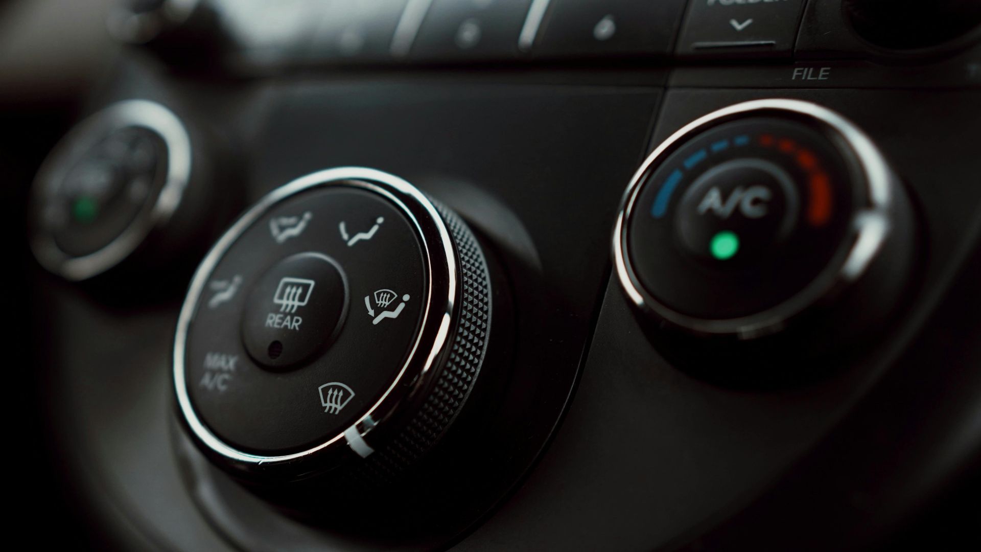 Detailed close-up of car dashboard air conditioning controls with focus on buttons and dials.