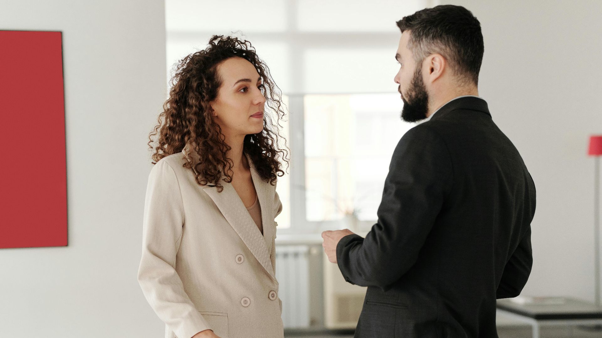 Two professionals engaged in a discussion in a bright, modern office setting.