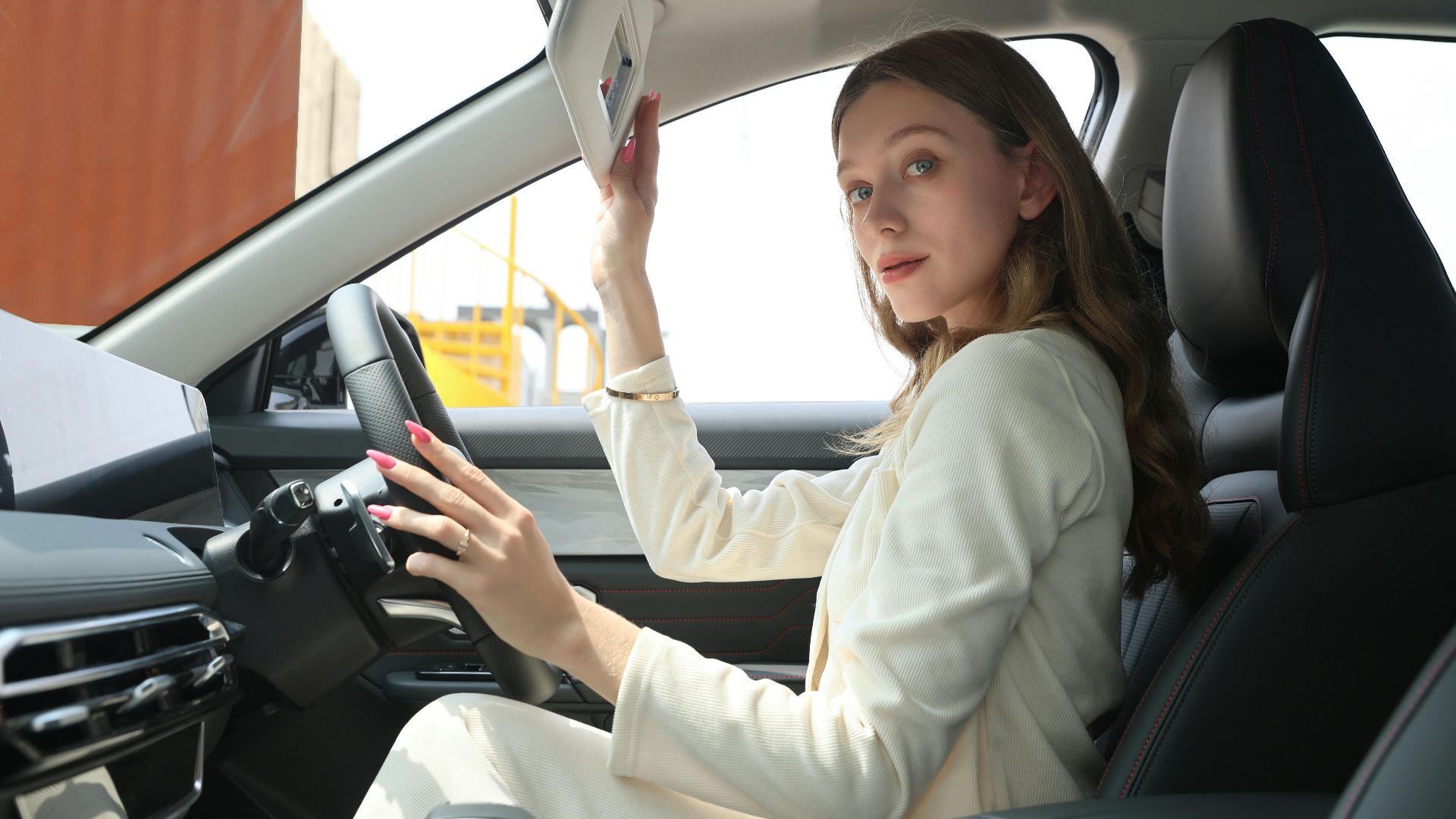 Stylish woman in an elegant car adjusting sun visor, emphasizing premium lifestyle and modern car interior.