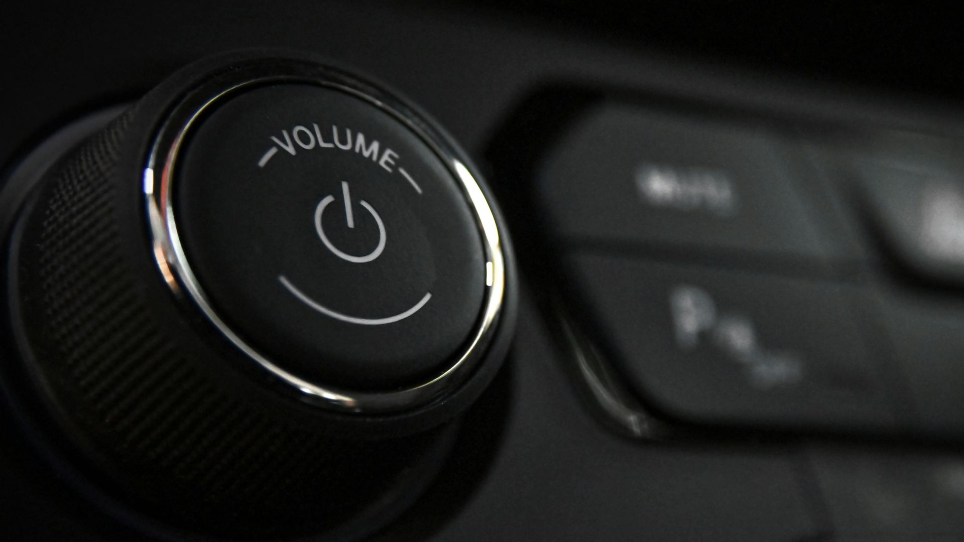 Detailed close-up of a vehicle's volume control knob and dashboard buttons indoors.