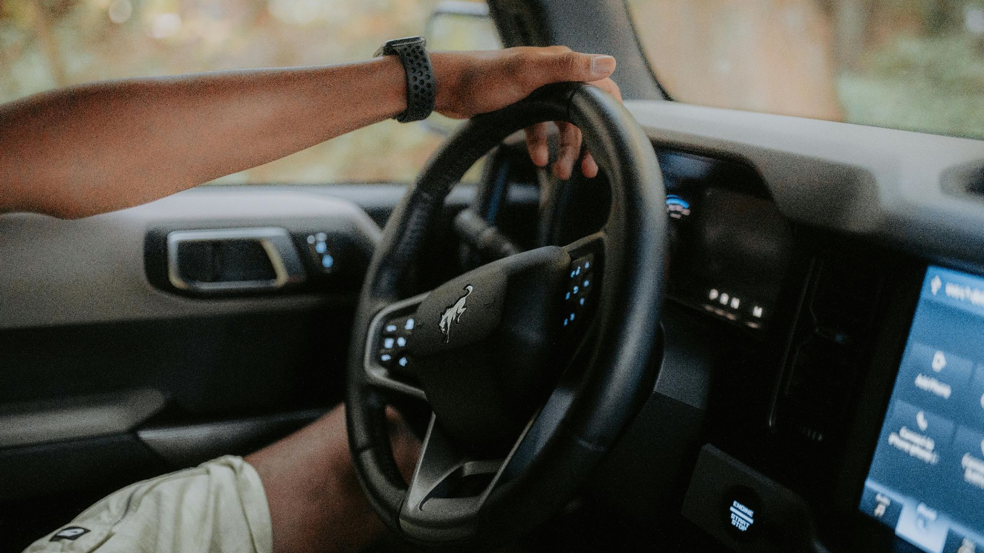 A person driving a modern car, focusing on hands and steering wheel.