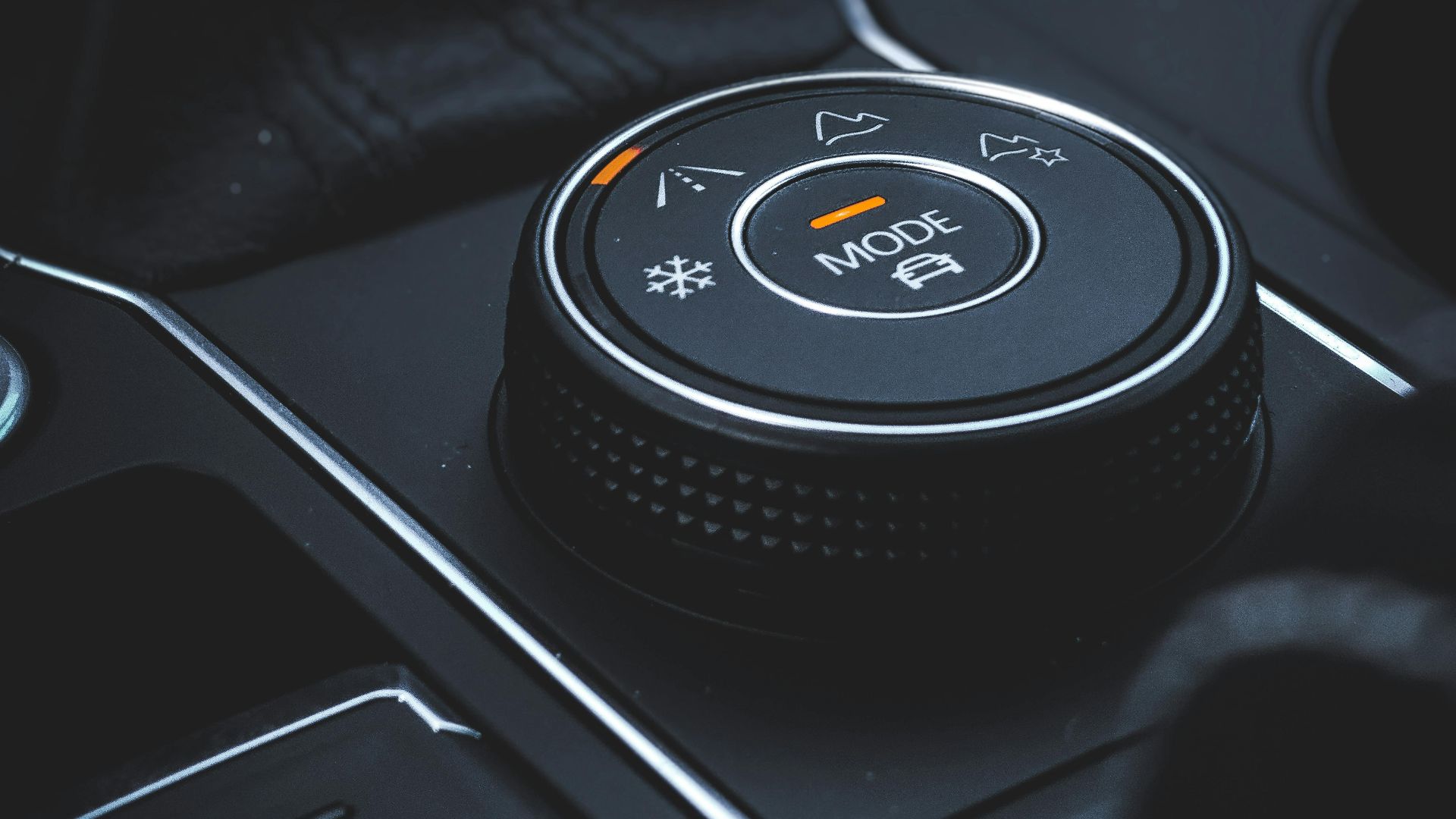 Detailed view of a car mode selector knob in a modern vehicle interior featuring technology and control elements.