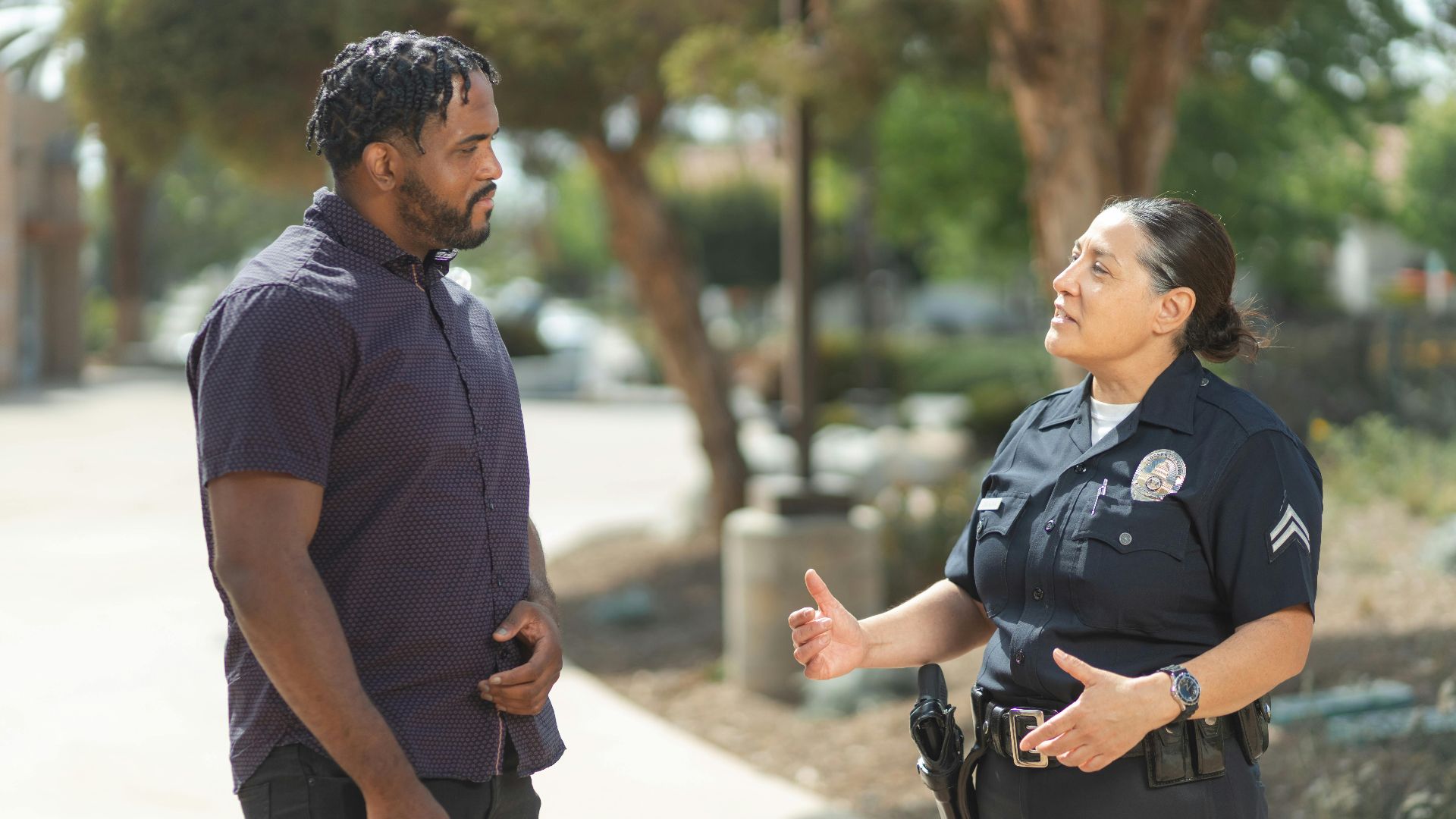 A police officer engaging warmly with a community member outdoors on a sunny day.