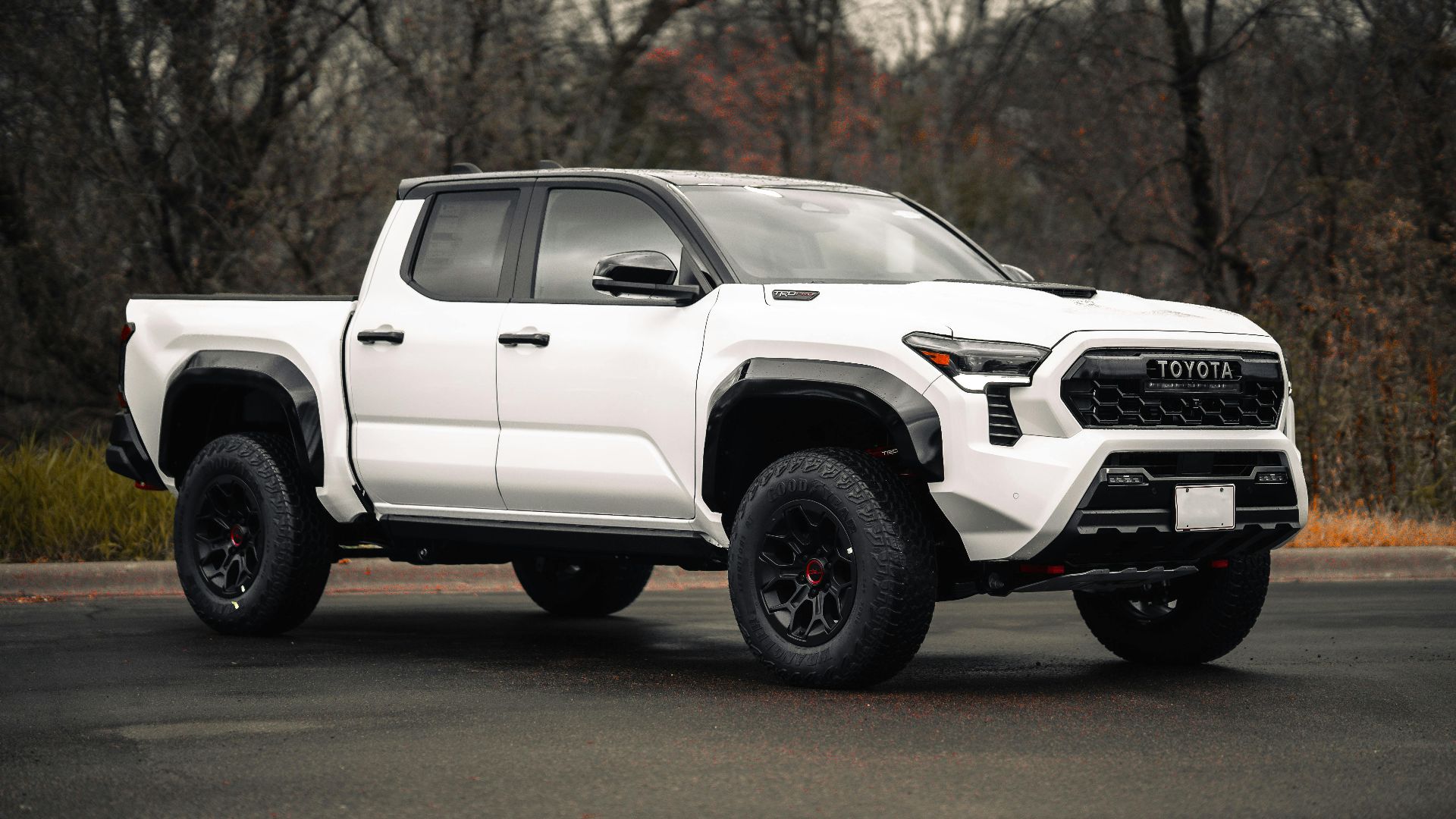 Sleek white pickup truck parked with forest backdrop, showcasing modern automotive design.