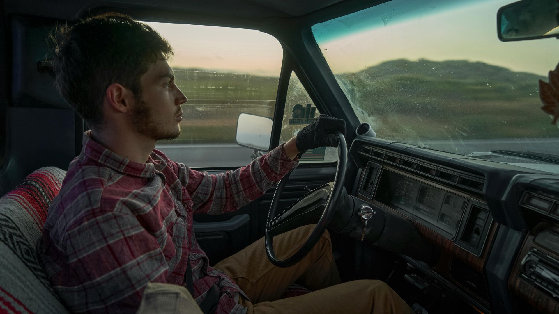 A young man drives a vintage car, showcasing scenic views and interior details.