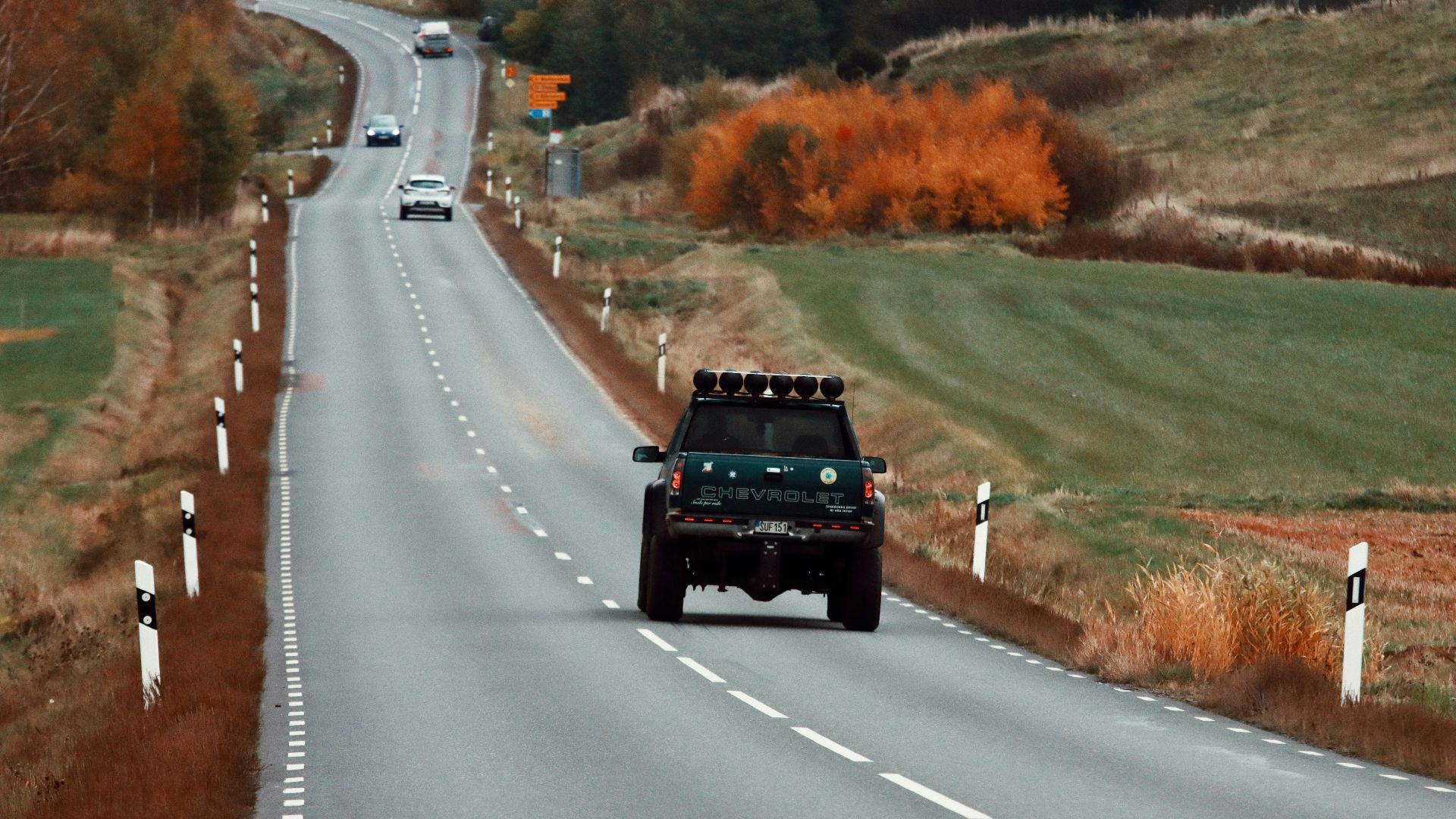 Pickup truck driving on a winding road in Huskvarna, Sweden, during autumn.