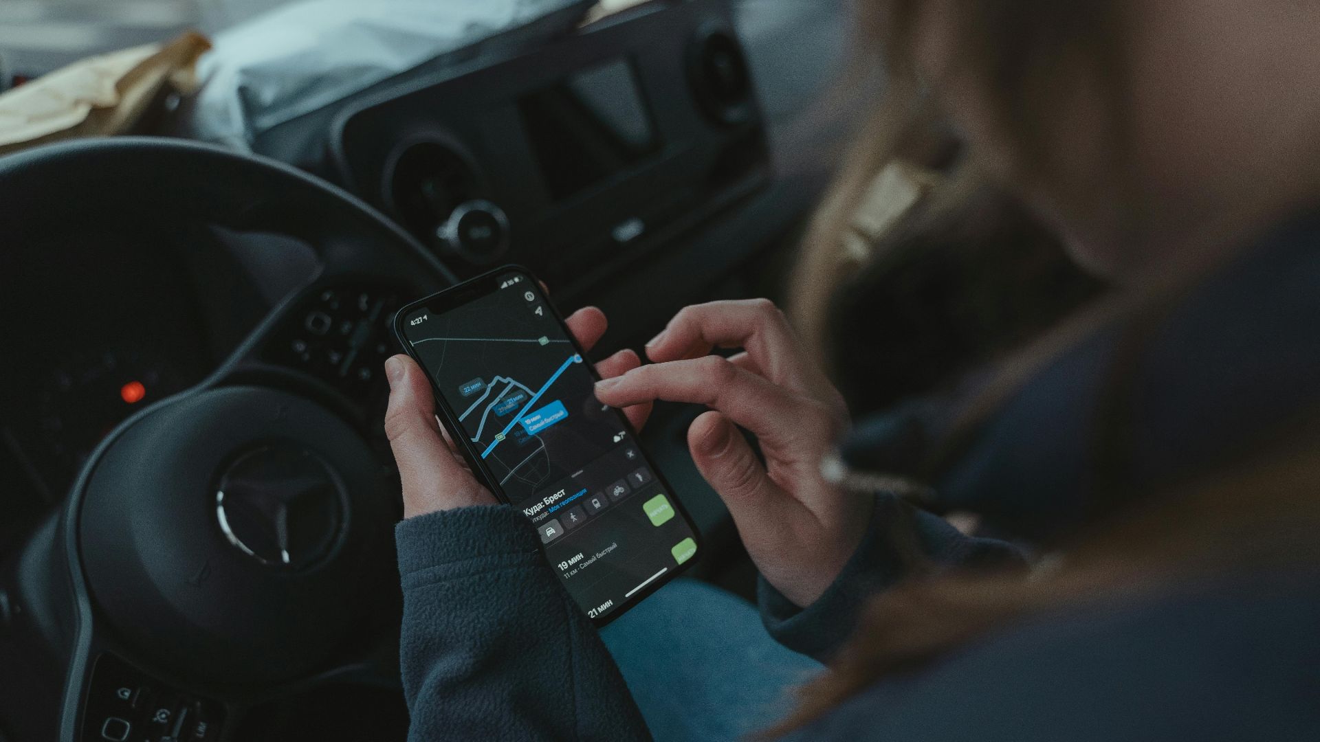 Person using GPS navigation app on smartphone inside car for directions.