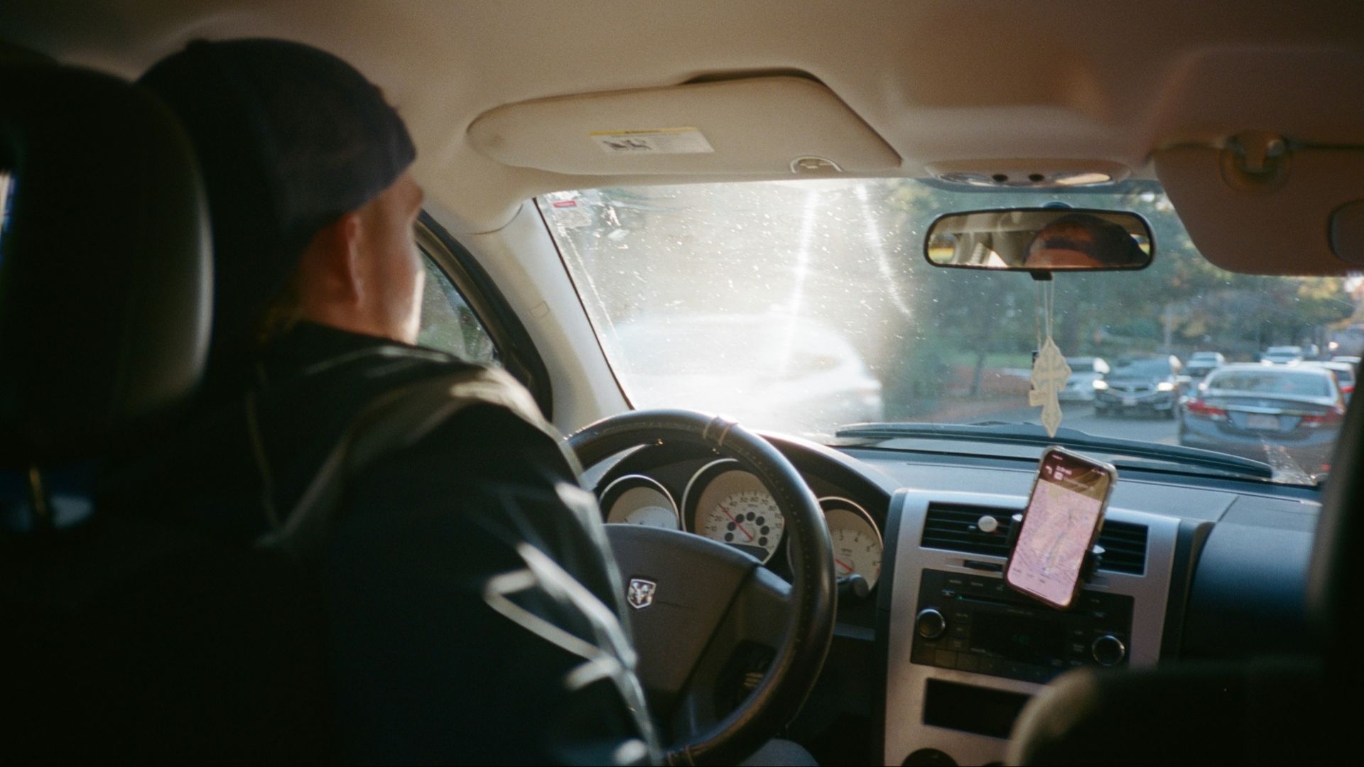 A man driving a car with a note on the dashboard