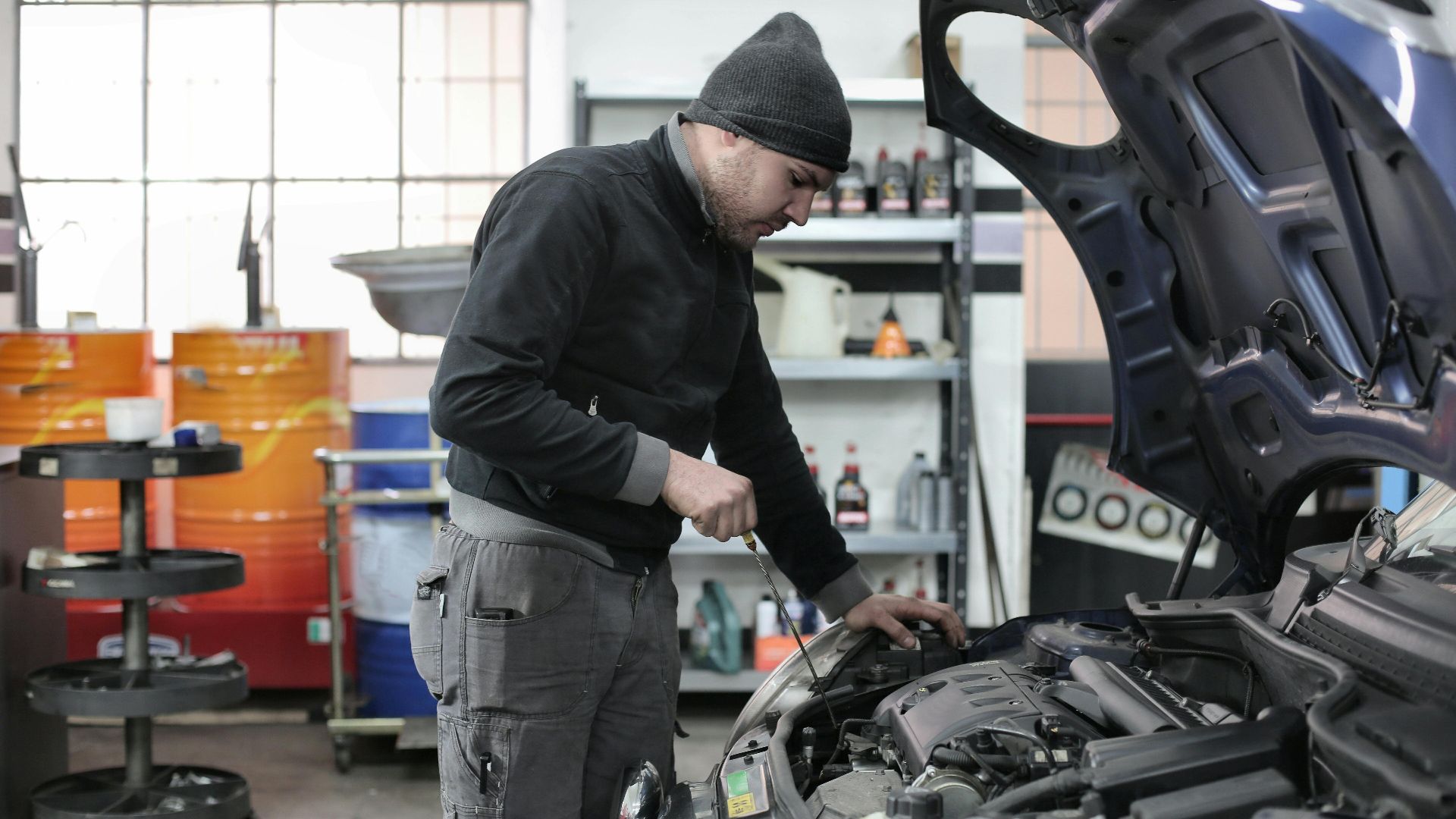 Mechanic checking a car engine in a garage, ensuring quality maintenance and repair.