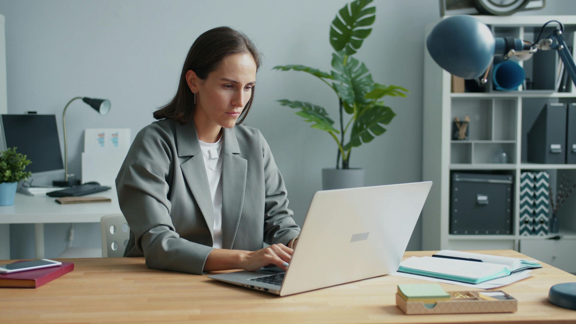 Businesswoman focused on laptop in modern home office setting.