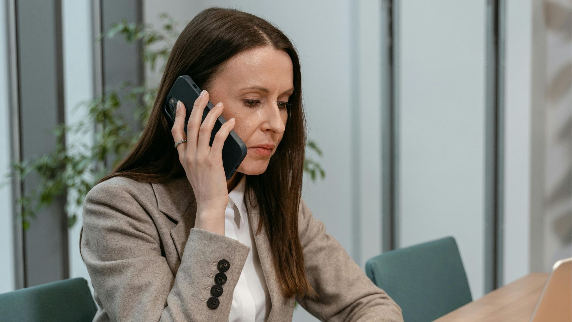 Focused businesswoman on a phone call at her office desk with a laptop.