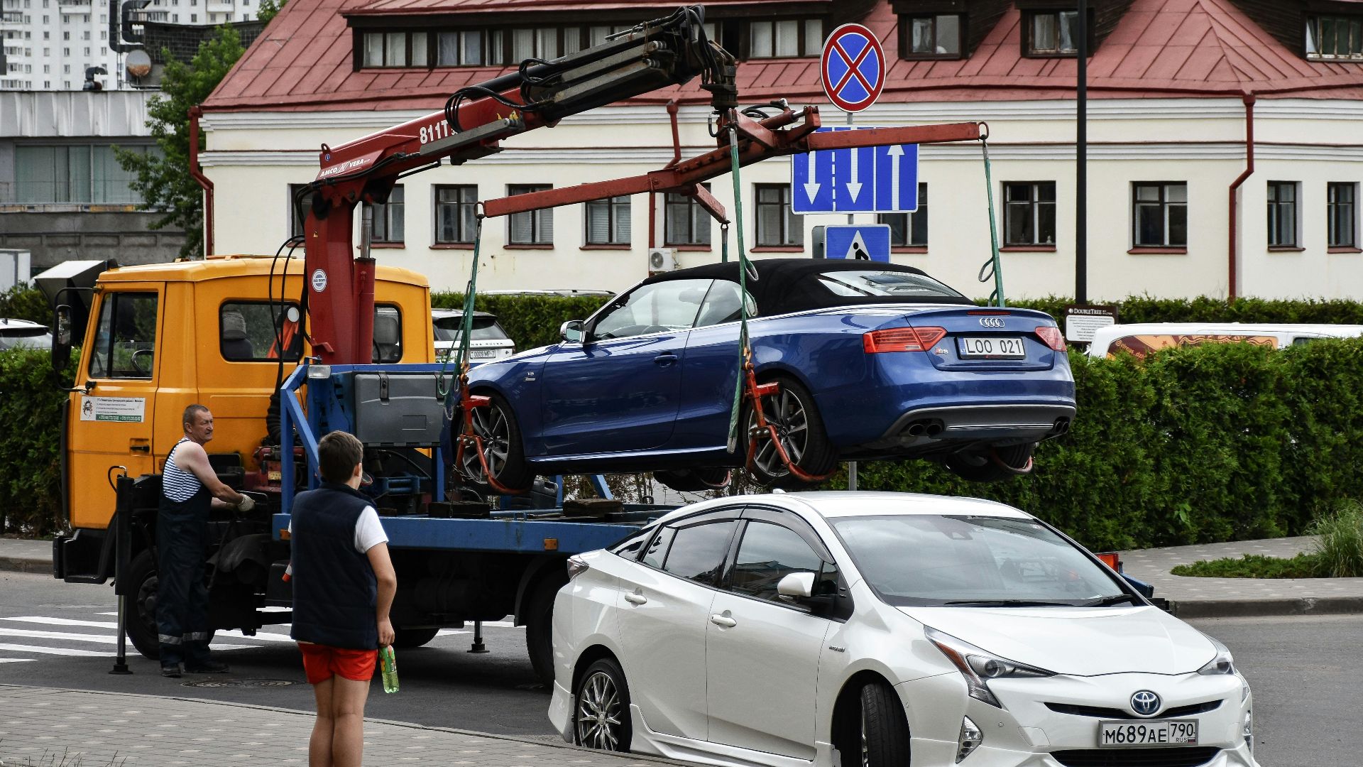 Towing a blue Audi convertible in a bustling city street.