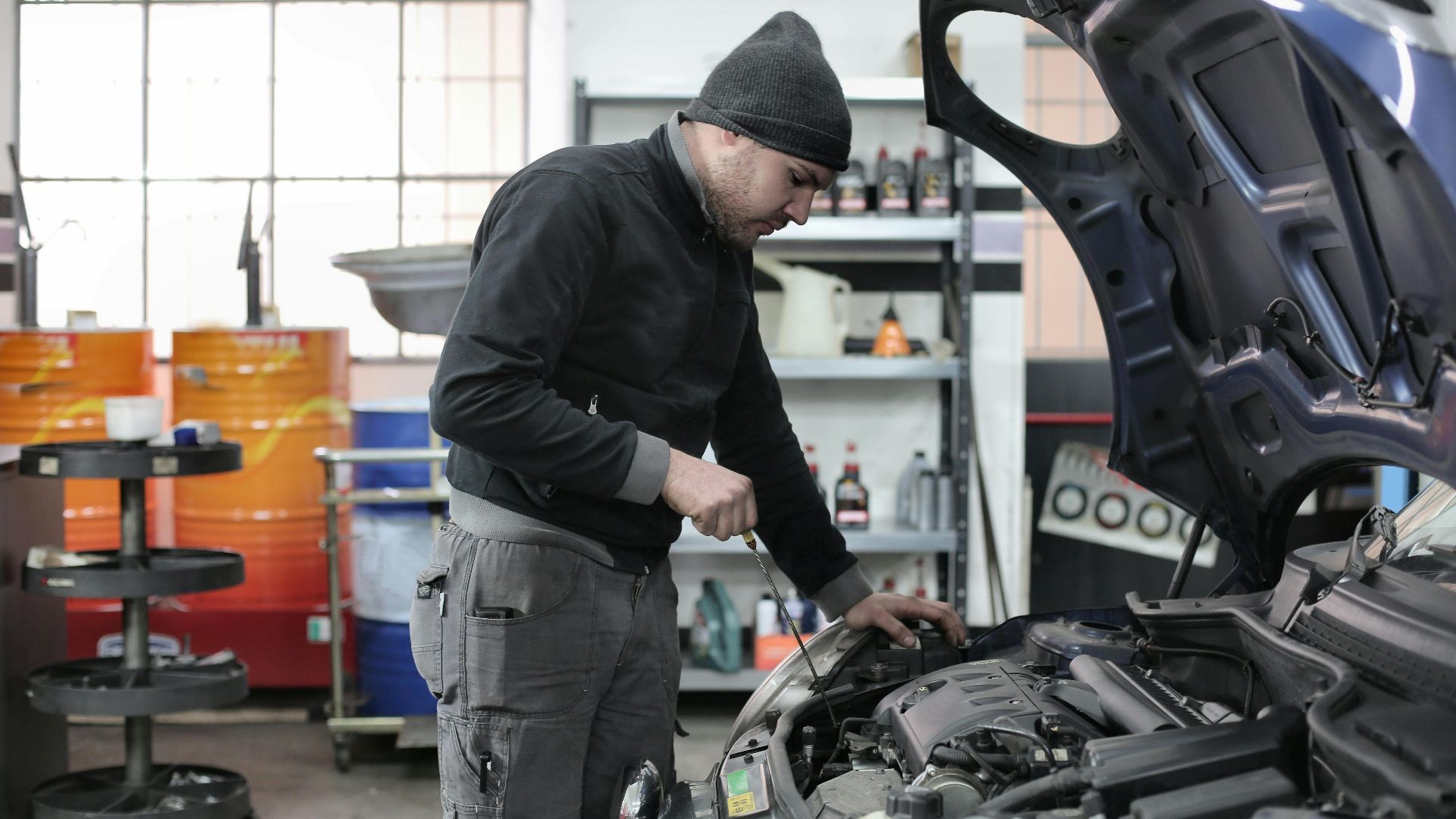 Mechanic checking a car engine in a garage, ensuring quality maintenance and repair.