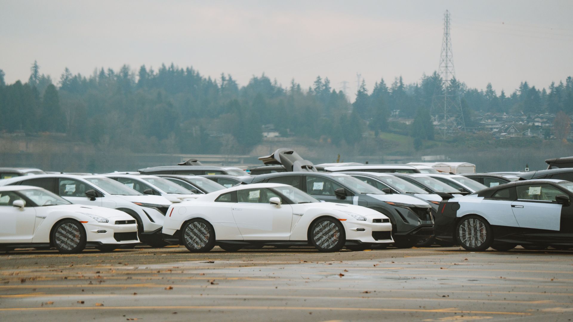Wide shot of multiple sports cars parked outdoors on a cloudy day.