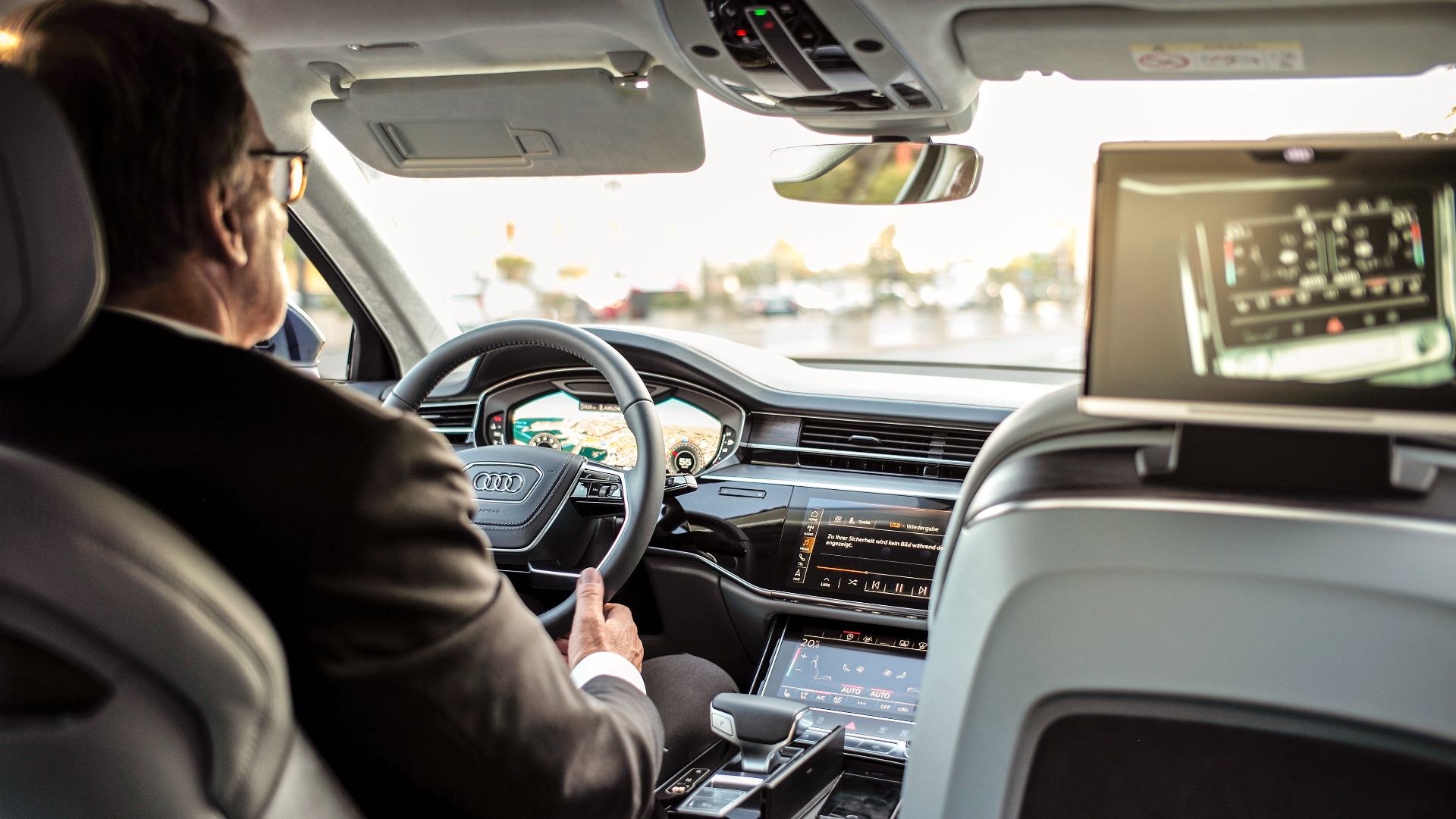 Businessman driving a modern luxury car, showcasing advanced dashboard and navigation systems for comfort and control.
