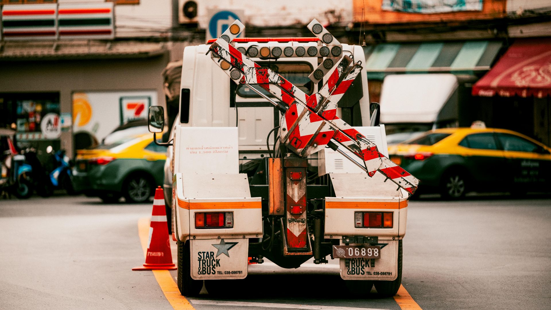 Utility vehicle with traffic barriers on a busy street in Bangkok, Thailand.