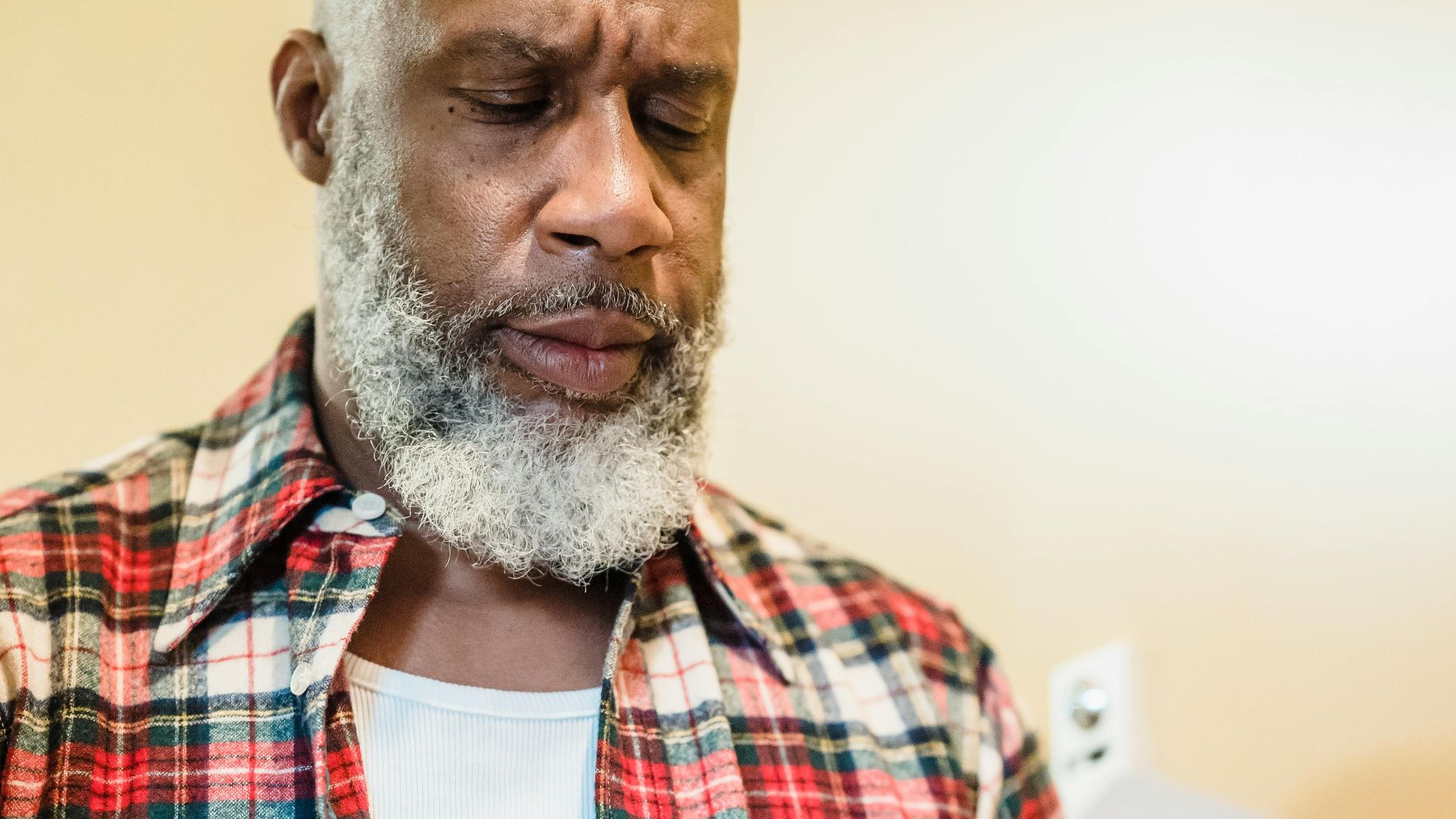 A mature man with a beard attentively reading documents indoors in a focused manner.