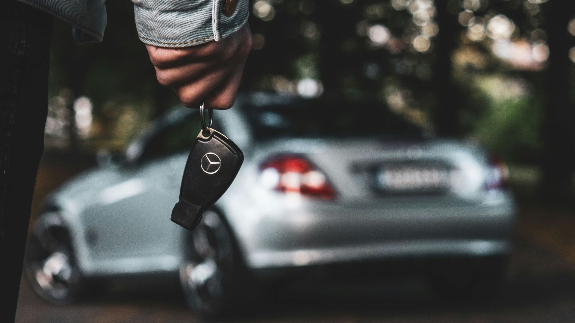 a person holding a car key next to a silver car