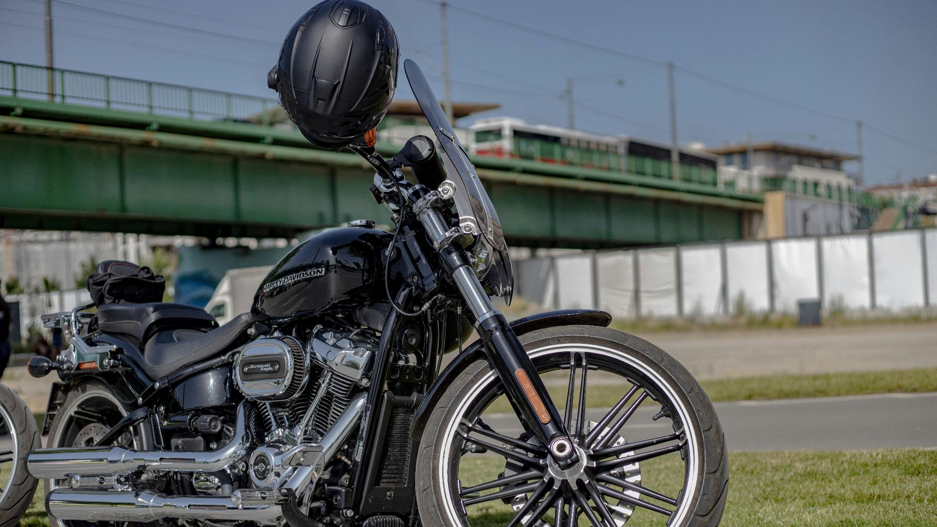 A stylish black Harley Davidson motorcycle parked outdoors with a helmet on the handlebars.