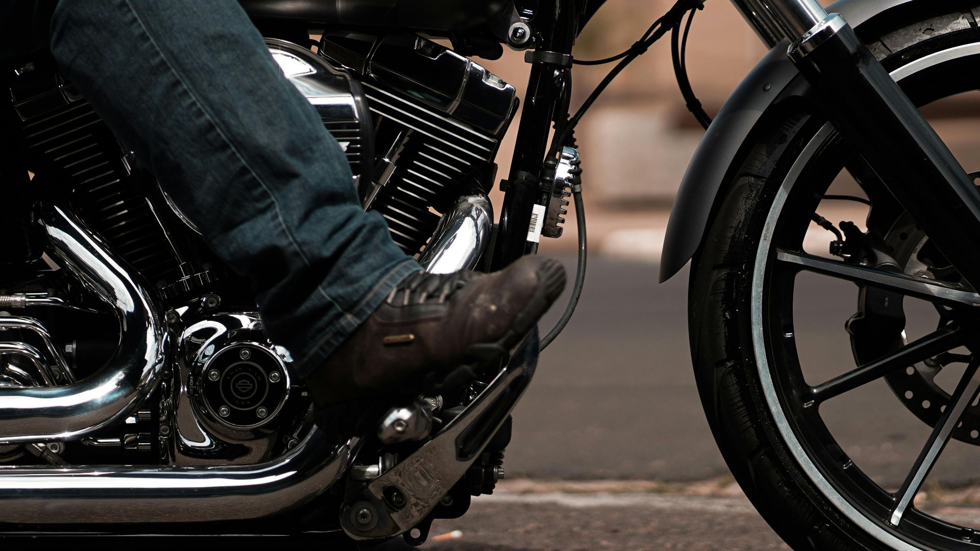 A close-up image of a biker in leather riding a motorcycle on an open road.