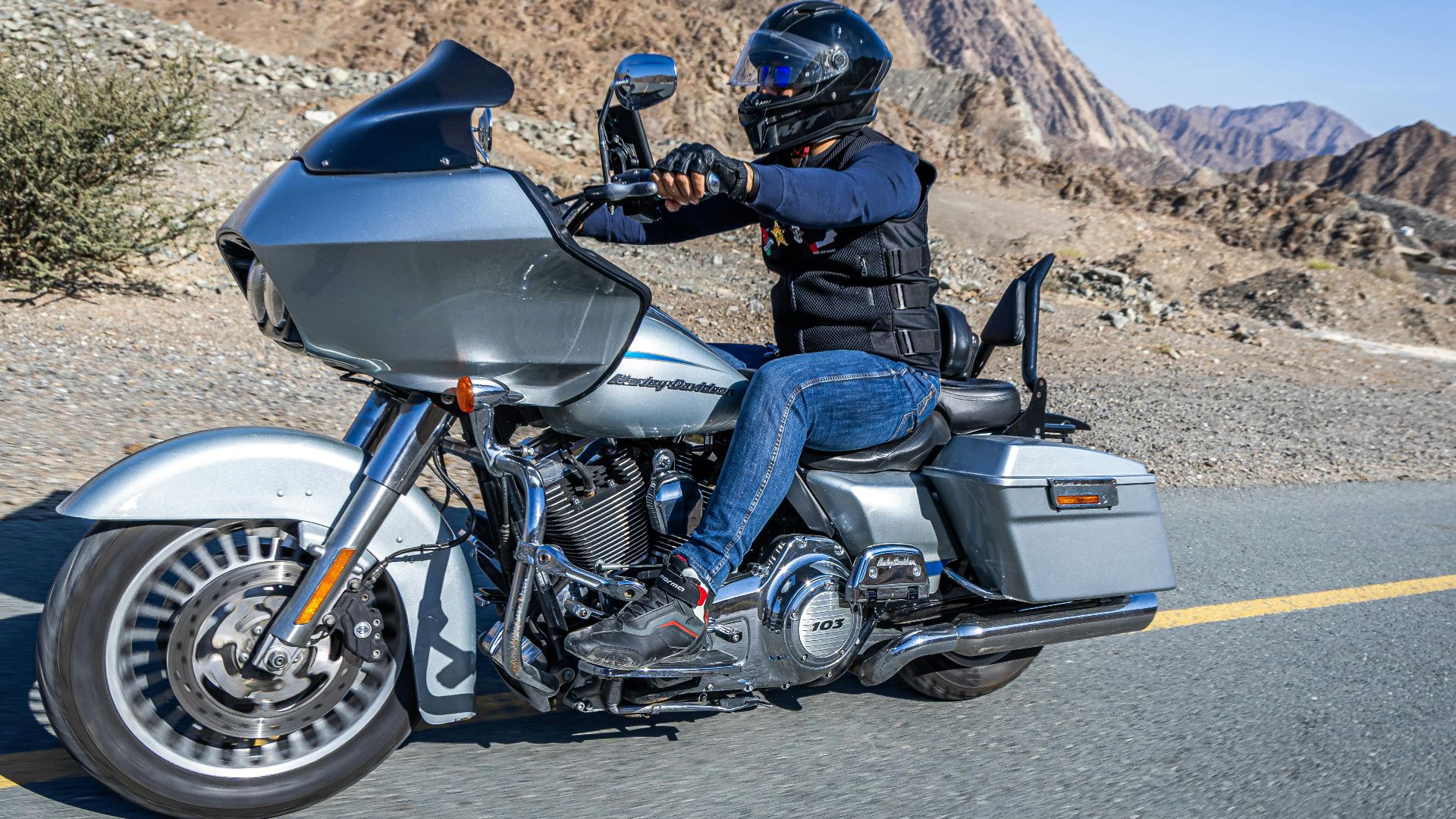 Motorcyclist cruising a Harley-Davidson through scenic Dubai mountains.