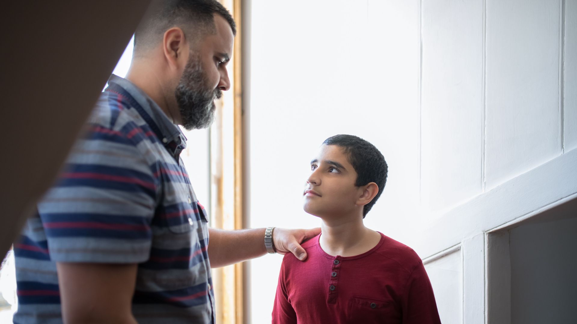 A father and son sharing a moment indoors, highlighting familial connection and bonding.