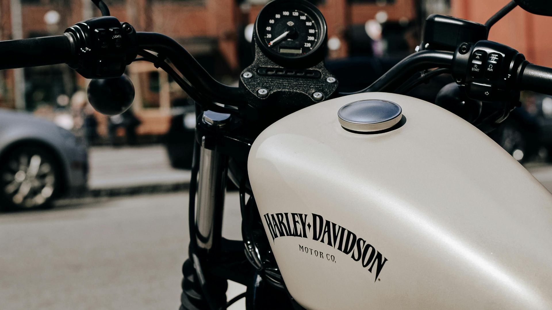 Retro styled white motorcycle with black handlebar parked on sunny street in city