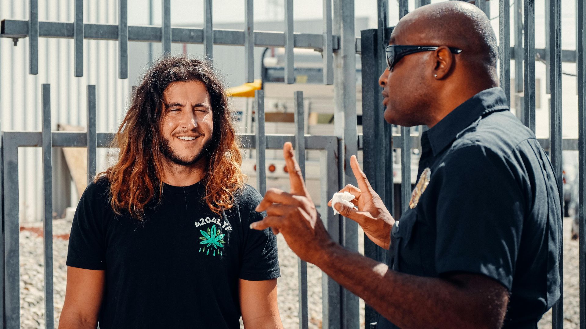 A police officer engages in conversation with a civilian outside on a sunny day.