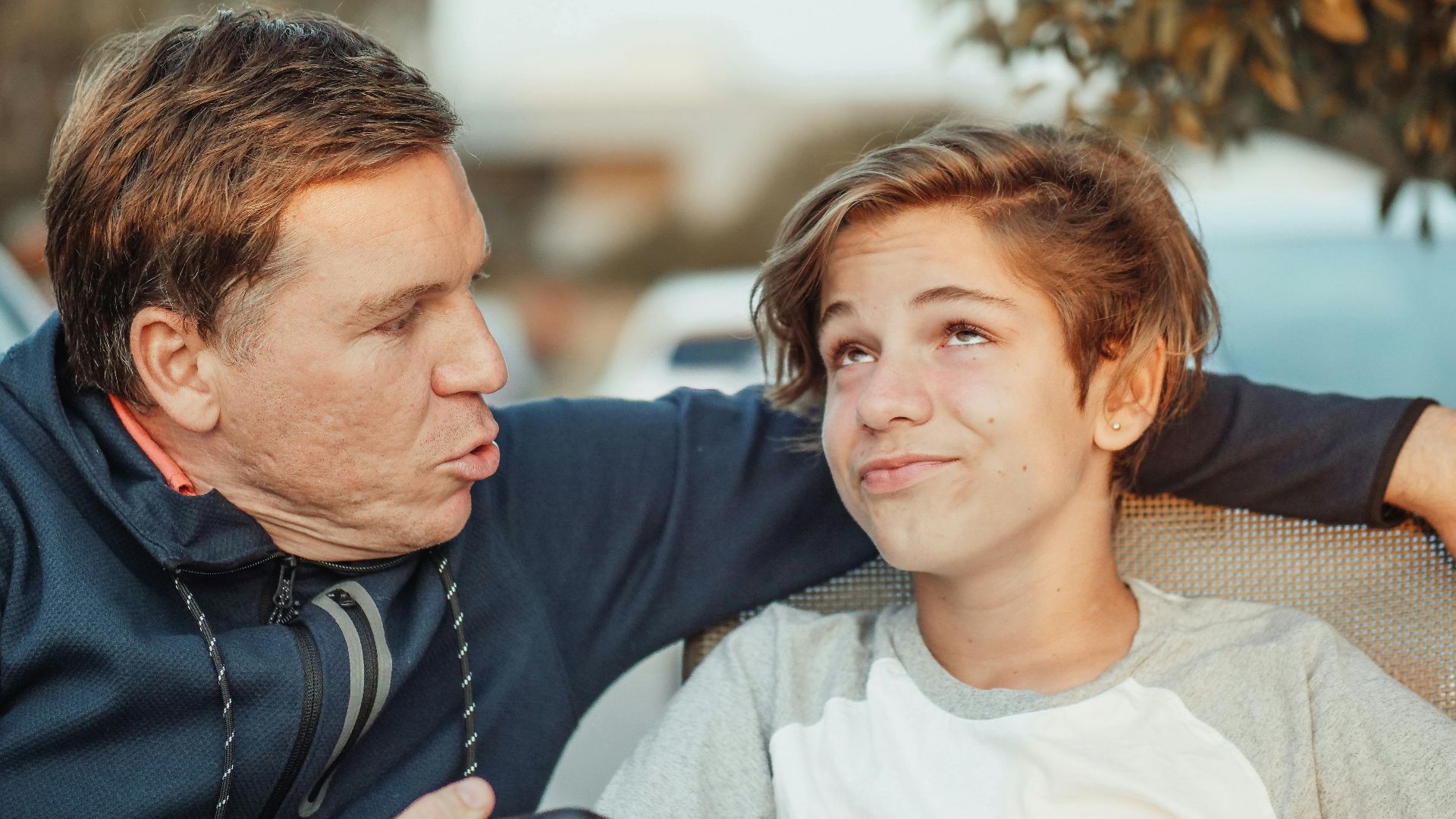 Playful interaction between father and son in a casual outdoor environment, captured in a candid moment.