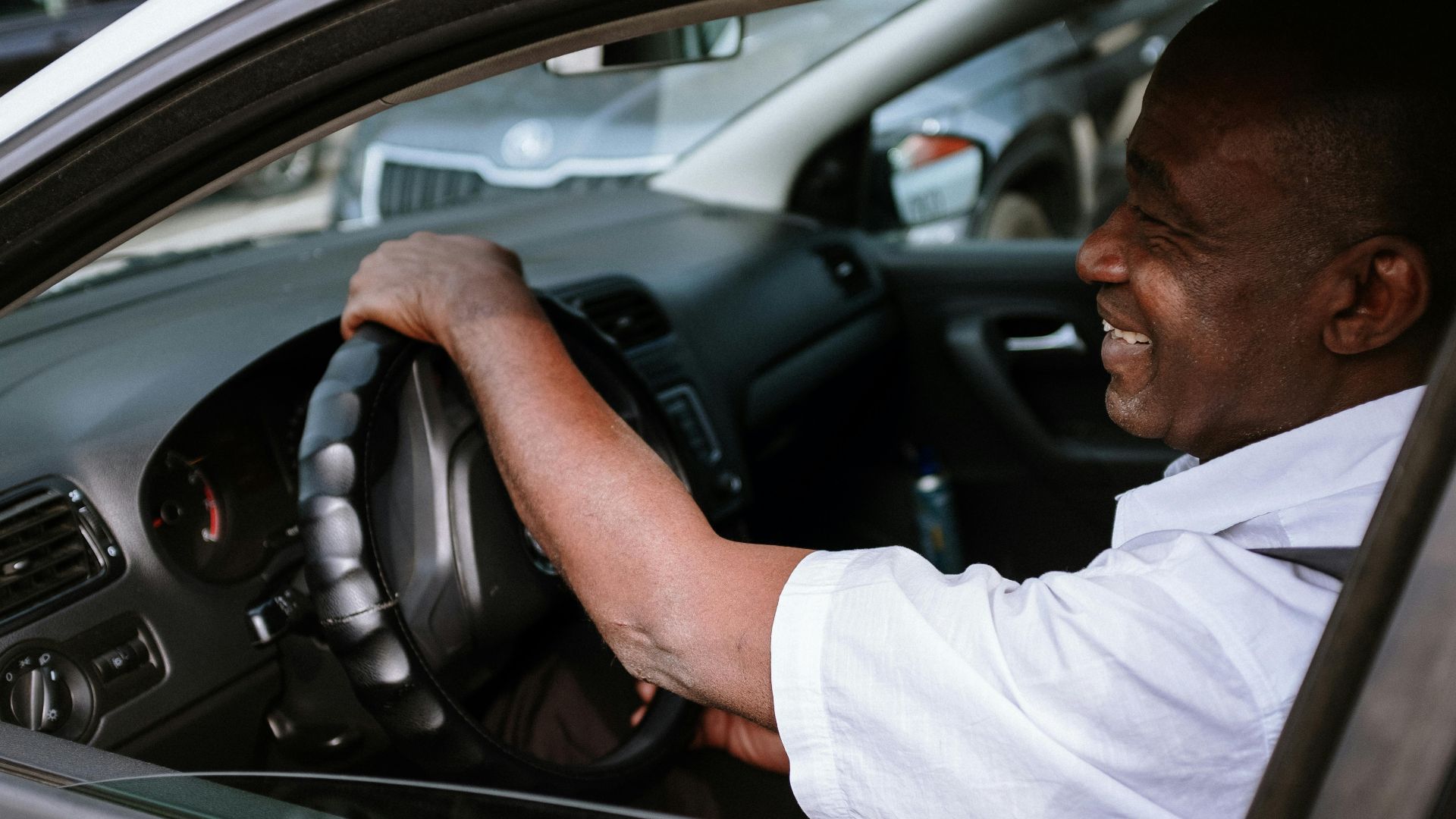 Smiling African American man in a car, enjoying a drive. Captured in a relaxed and candid moment.
