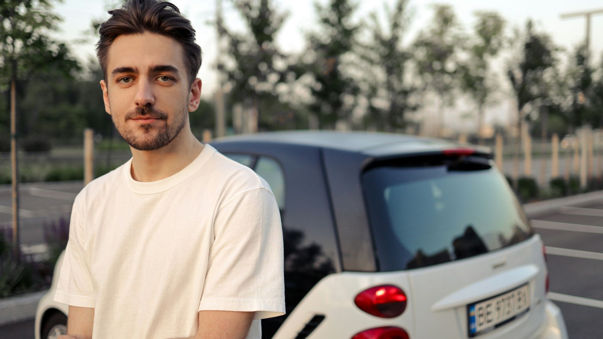 man in white crew neck t-shirt standing beside white car during daytime