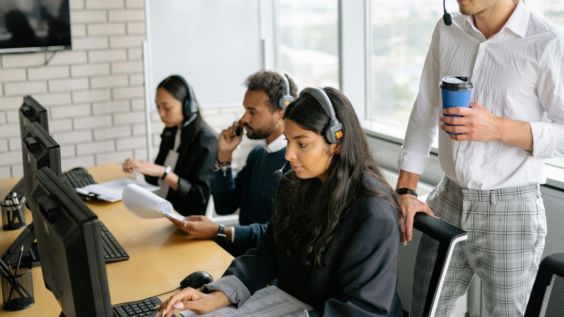 A diverse group of employees working together in a bright, modern call center with headsets.