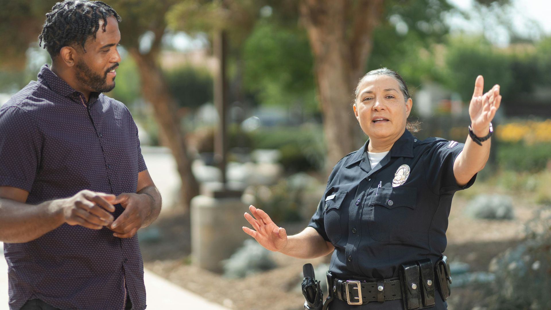 Police officer in uniform engaging in a conversation with a man on a sunny day, promoting community relations.