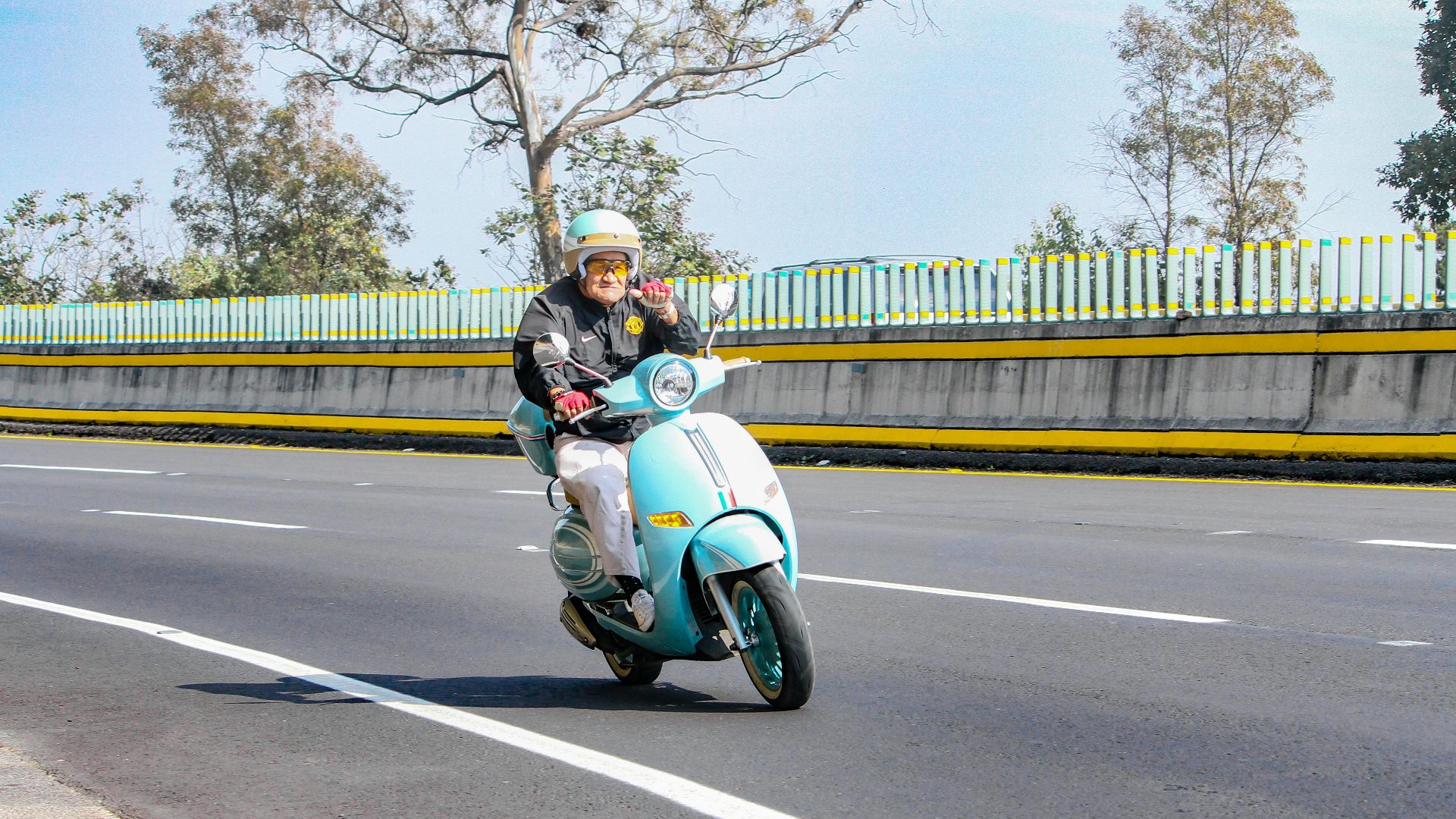 Elderly man riding a blue scooter on a sunny day, showcasing freedom and adventure.
