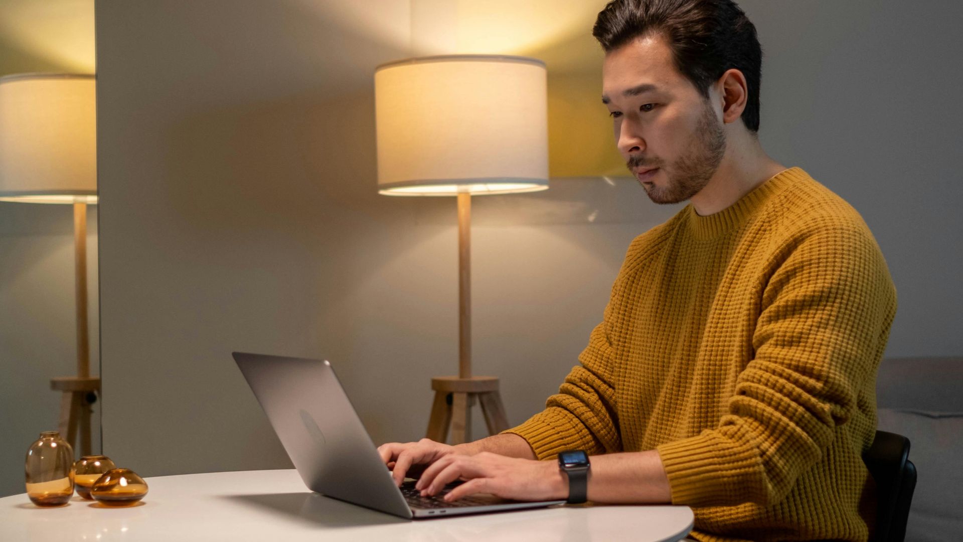 Asian man working on laptop at home in a stylish living room with modern interior design.