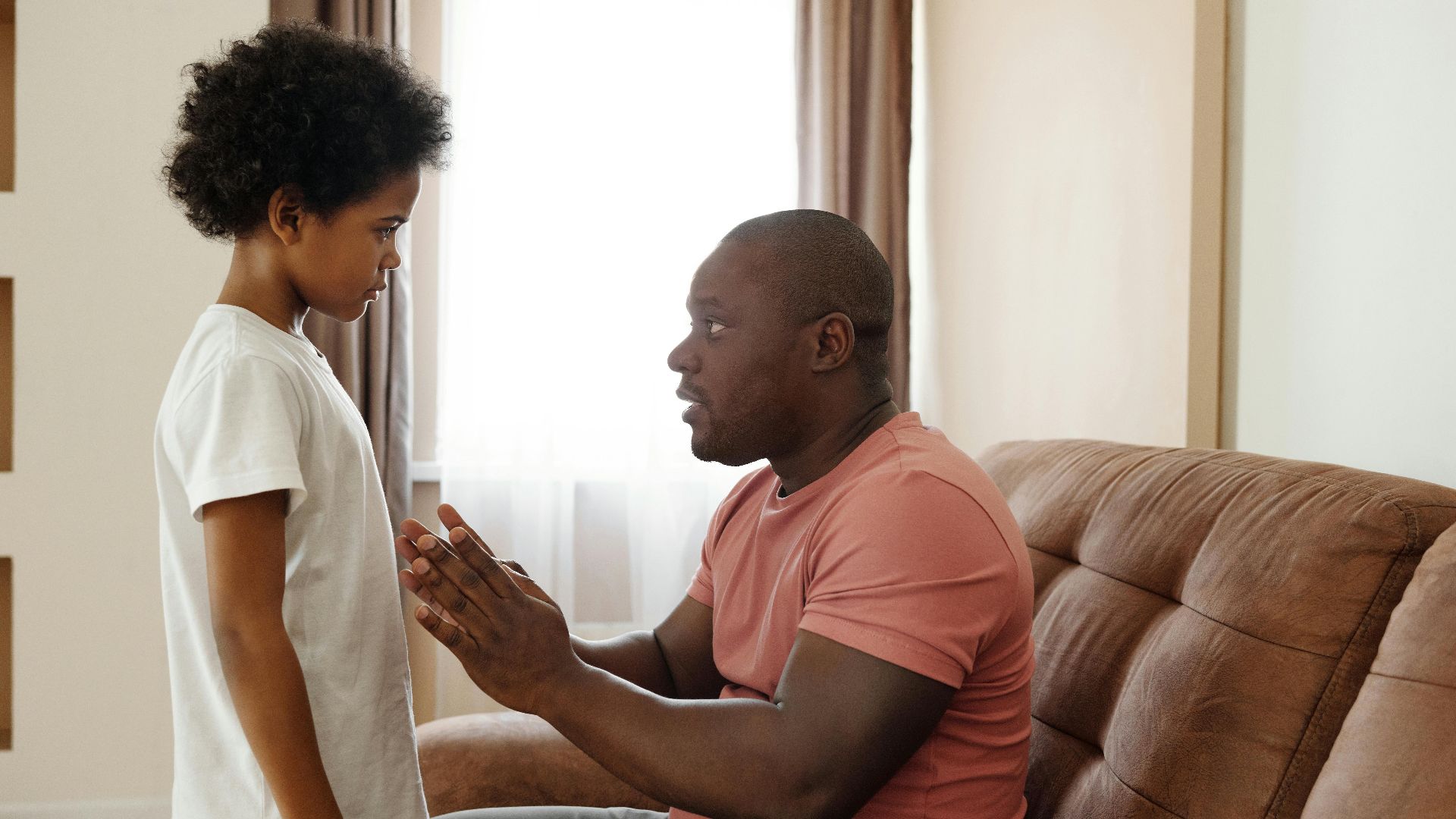 A father and son sharing an intimate conversation in a cozy living room setting.