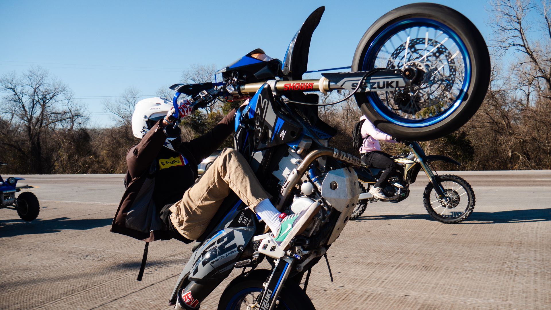 This is a super-moto motorcycle (Suzuki DRZ 400sm) preforming a wheelie in a private stunt lot.