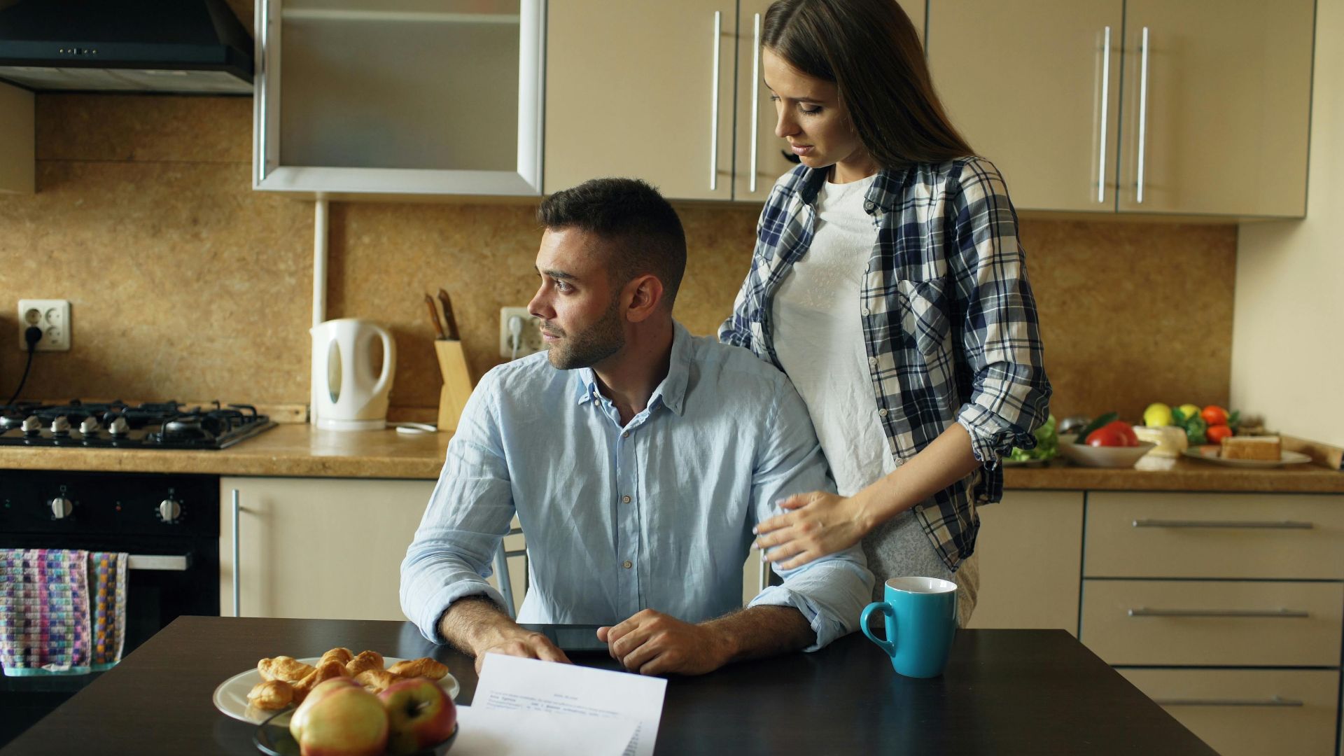 A couple having a serious discussion over breakfast papers in a modern kitchen.