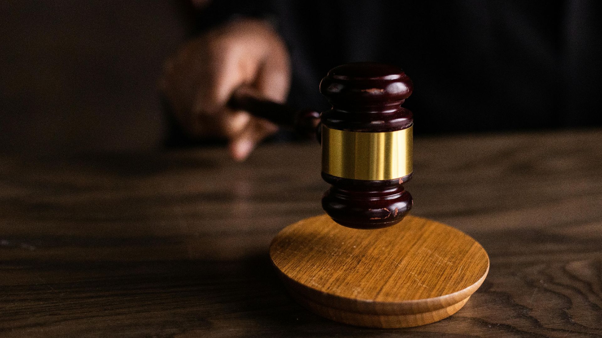 A gavel striking a sound block, symbolizing justice and legal authority in a courtroom setting.